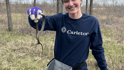 A Carleton student poses with a snake in the Arb